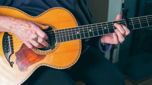 close up of hands playing an acoustic guitar