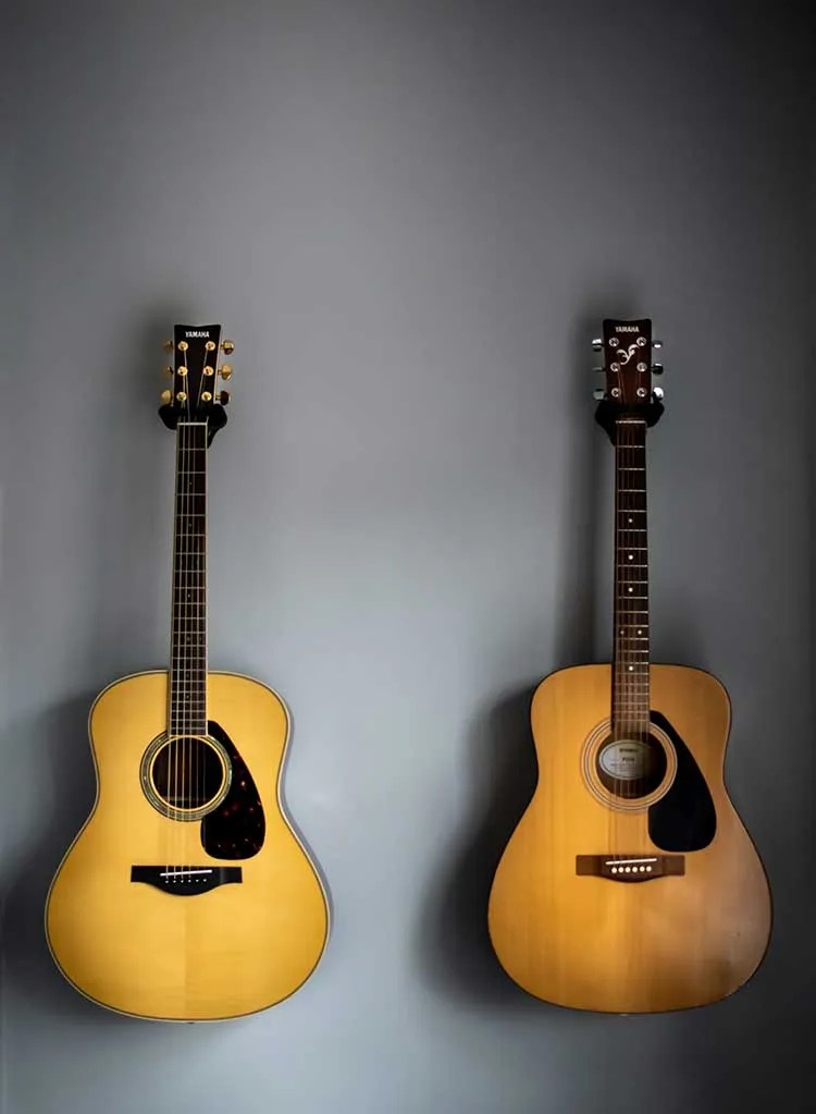 two acoustic guitars hanging on the wall