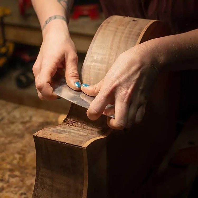 Maegen Wells scraping the sides of a guitar in progress