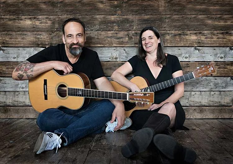 Jamie Stillway and Eric Skye seated, holding acoustic guitars