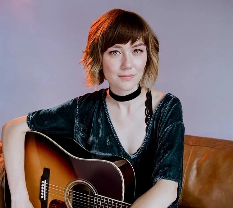 Molly Tuttle on couch with guitar 