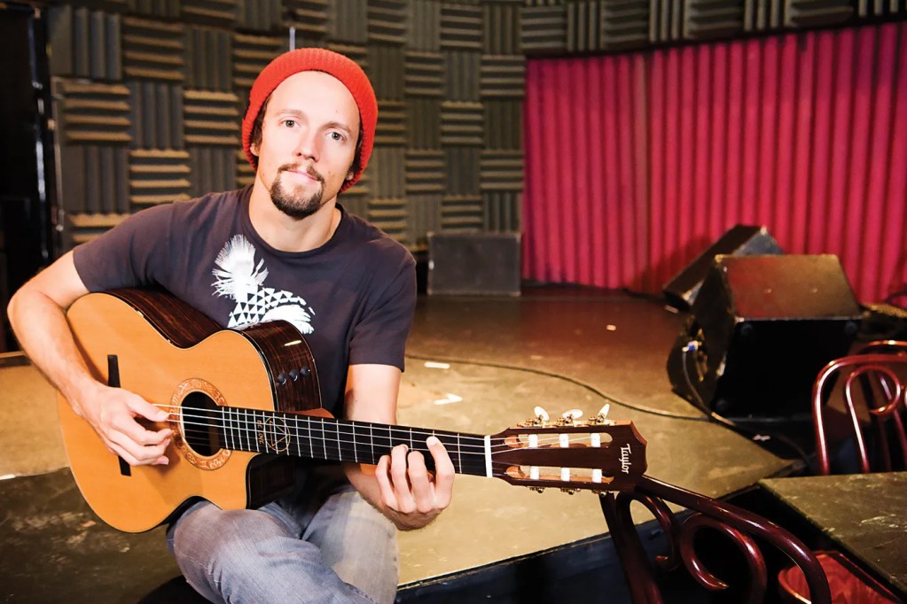 Jason Mraz poses with his guitar in a studio