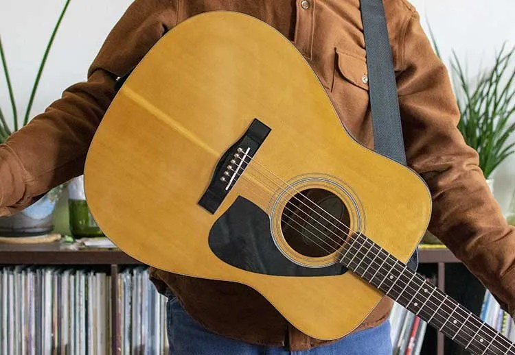 guitarist with an acoustic guitar on a strap