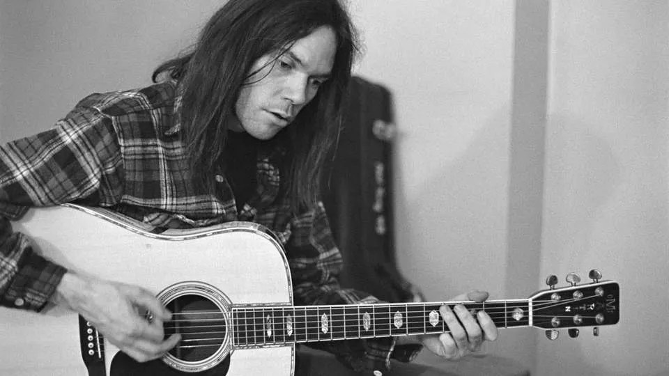 Neil Young playing an acoustic guitar