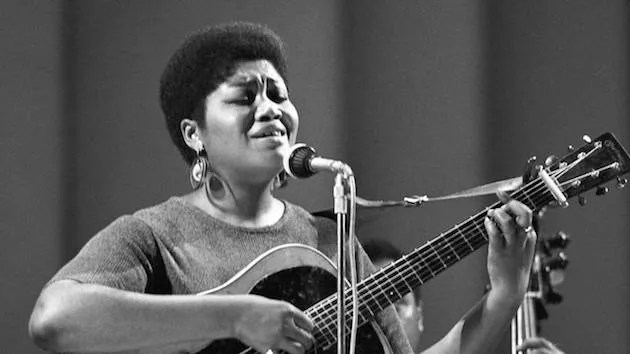 Odetta playing guitar and singing on stage