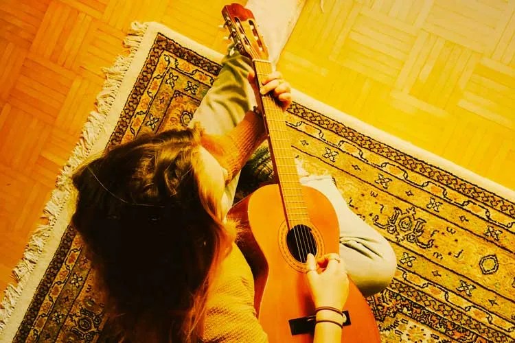 photo of guitar student seated on a rug taken from above