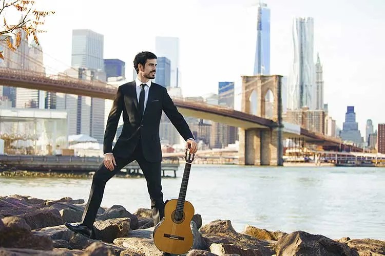 Pablo Sainz-Villegas on the river banks beneath a bridge with classical guitar