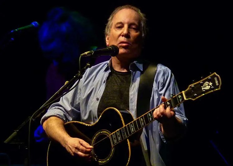 Paul Simon playing guitar onstage