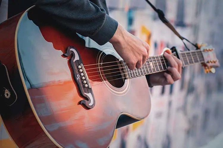 closeup of a guitarist holding and playing an acoustic guitar