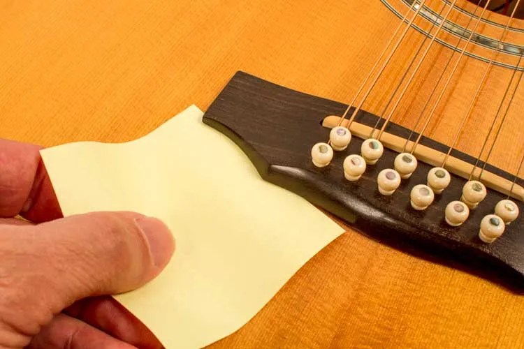 A piece of paper is slipped under a loose guitar bridge.