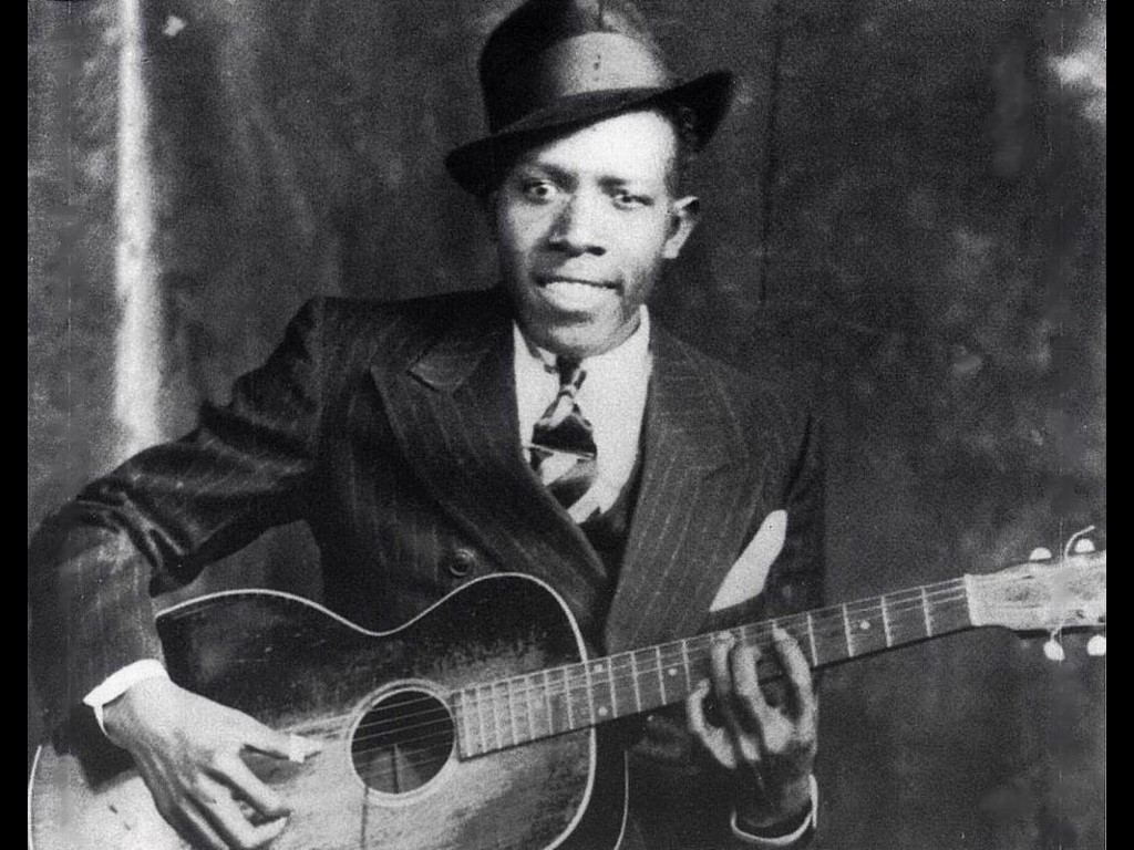 bluesman Robert Johnson seated holding acoustic guitar