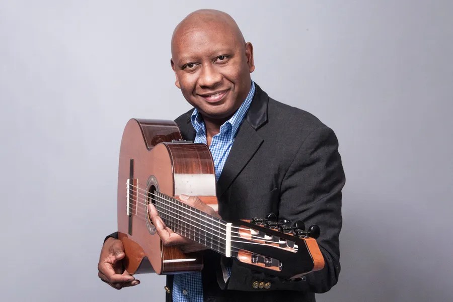 ron jackson posing with his acoustic guitar pointed headstock first towards the camera