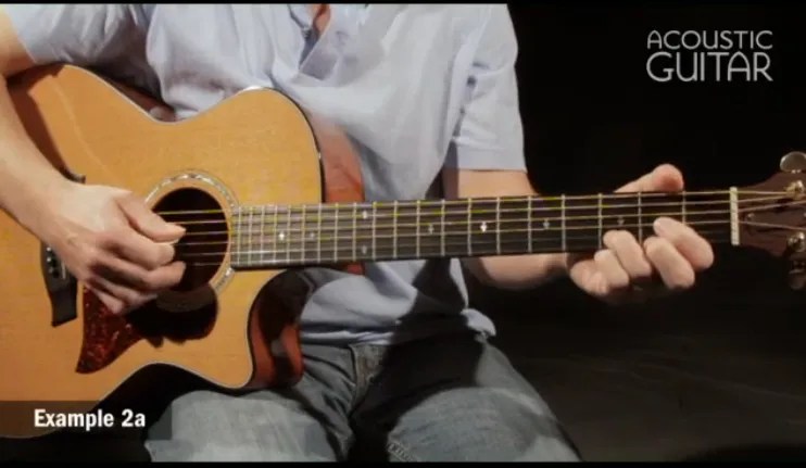 closeup of hands playing an acoustic guitar