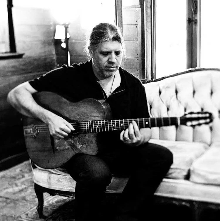 Stéphane Wrembel playing guitar on a couch