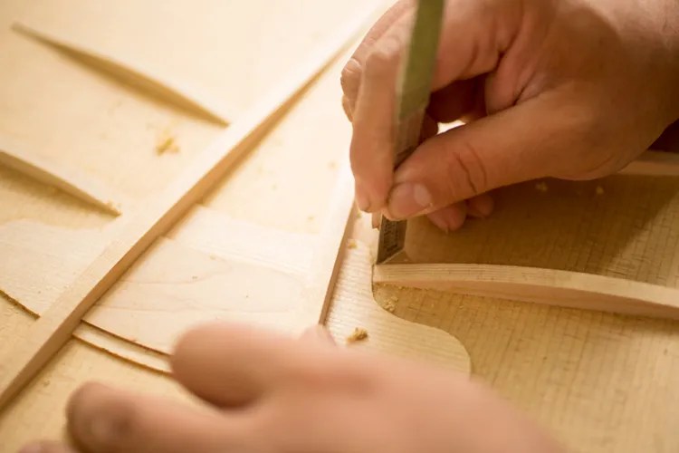 A luthier applies glue to an acoustic guitar soundboard - Taylor Guitars' new V-Class bracing