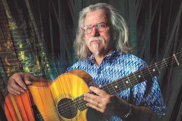 Tim Sparks holding an acoustic guitar.