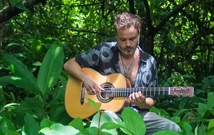 Twanguero playing acoustic guitar in costa rica jungle.