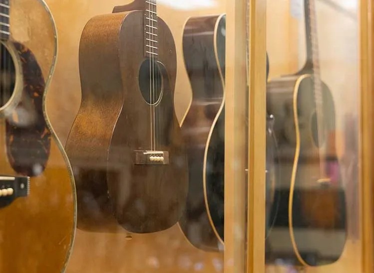 Vintage acoustic guitars hanging on a music store wall.