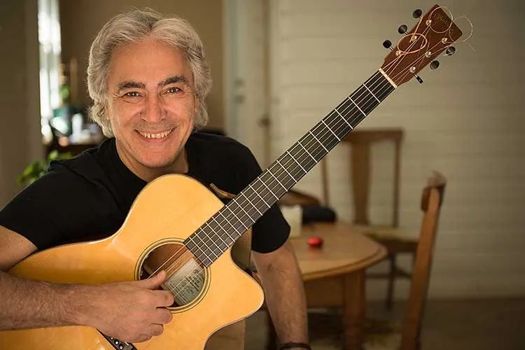 Portrait of Woody Mann holding an acoustic guitar - photo by Rod Franklin